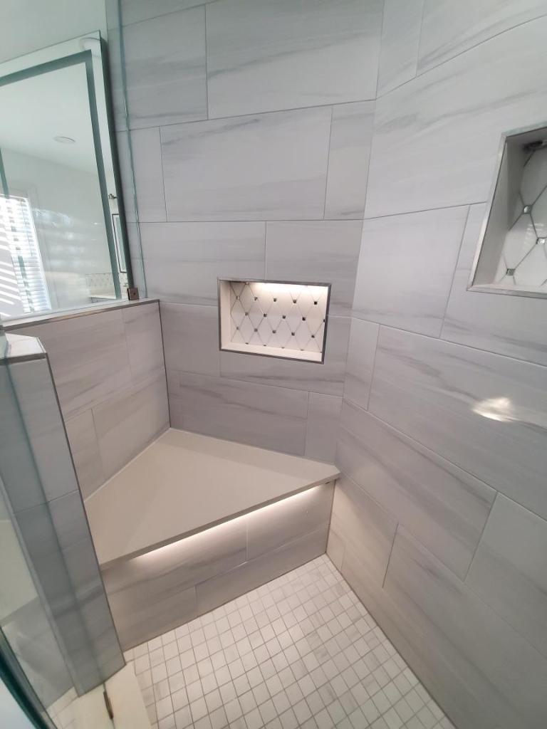 Bathroom remodeling project featuring large wall tiles and a bench in the shower